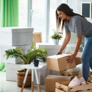 Image shows a woman moving packed boxes in a well-lit room